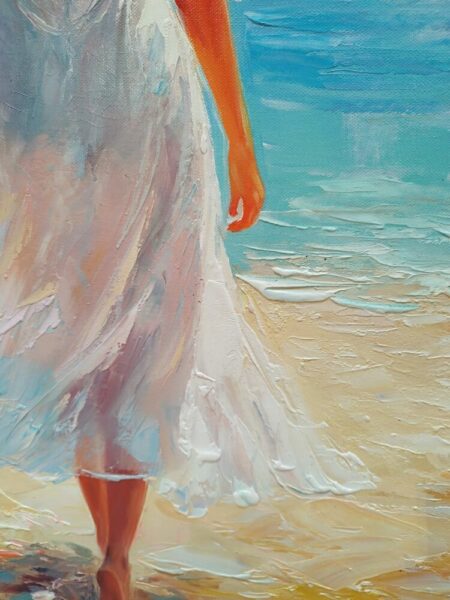 Partial view of a person walking on the beach in a flowing white dress, with turquoise sea behind them.