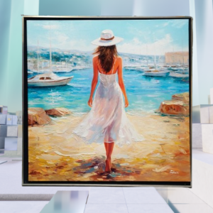 Framed painting of a woman in a white dress and hat walking toward the sea on a sunny beach, seen from behind.